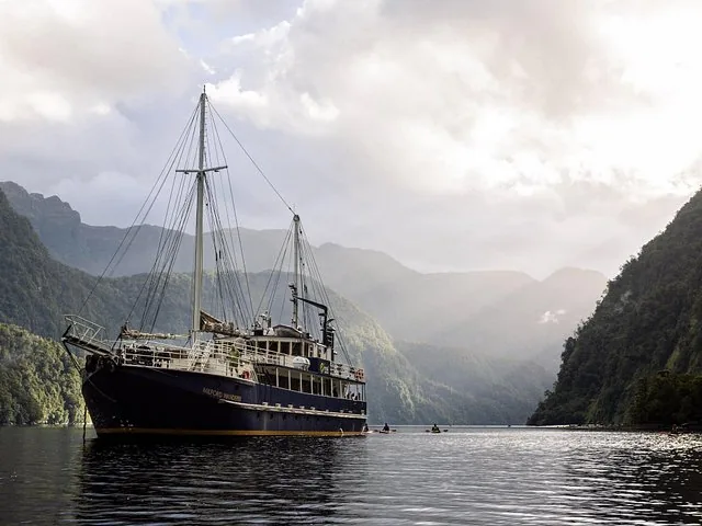 Ein großes Kreuzfahrtschiff durchquert die ruhigen Gewässer des Doubtful Sound, umgeben von Bergen.