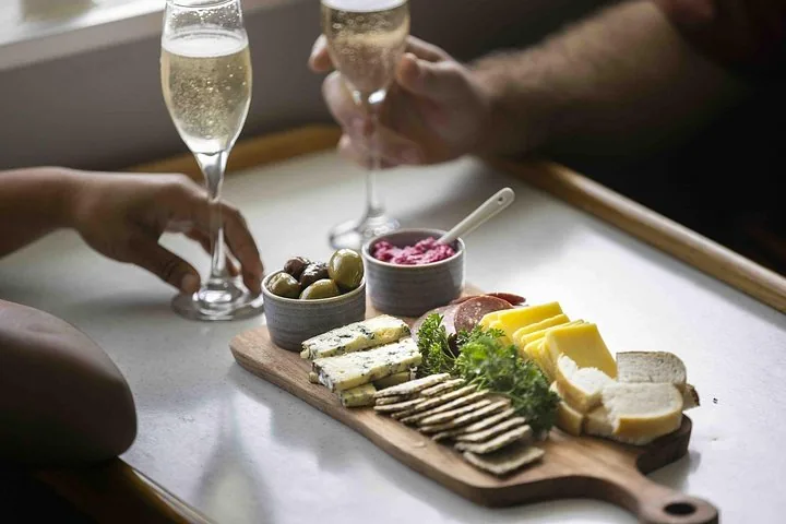 Eine Käse- und Snackplatte mit Gläsern Champagner, auf einem Boot serviert.